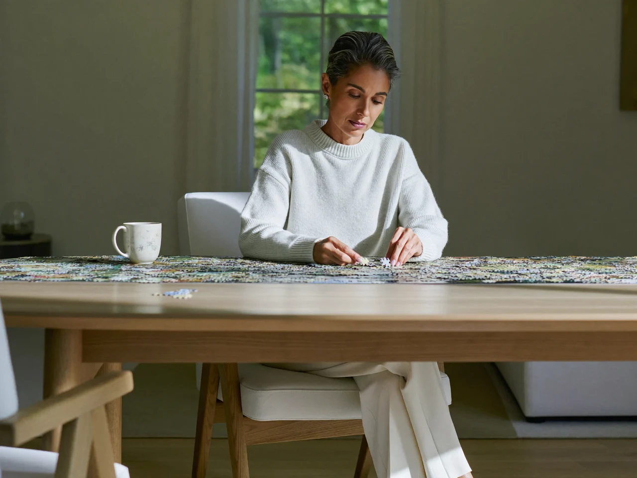 Grande table de salon avec un puzzle à moitié assemblé et une tasse de thé