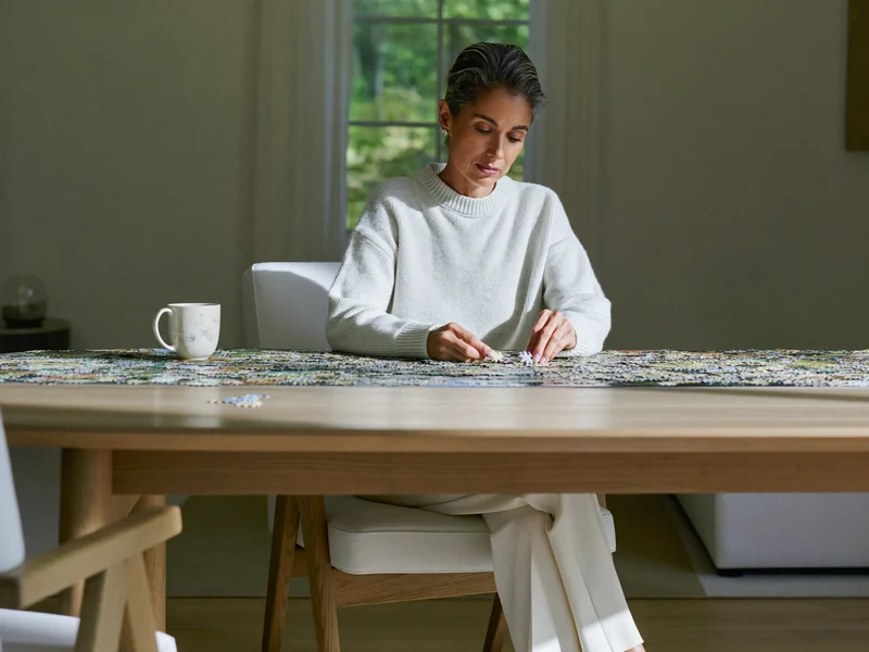 Grande table de salon avec un puzzle à moitié assemblé et une tasse de thé
