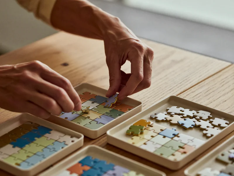 Mains triant des pièces de puzzle par couleur dans de petits plateaux